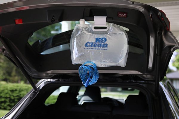 A picture of the Portable Pet Shower hanging from the back of a hatchback vehicle.